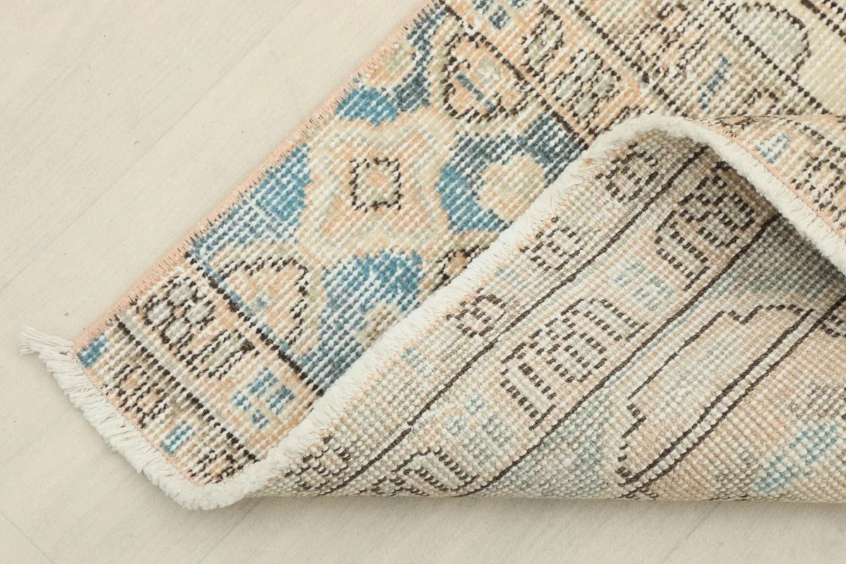 Corner of the rug folded back to show the cotton foundation and the reverse side of the knots.