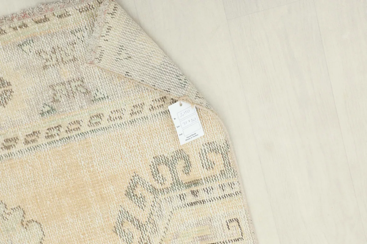 Corner of the rug with a product tag, showing the reverse side and hand-knotted construction
