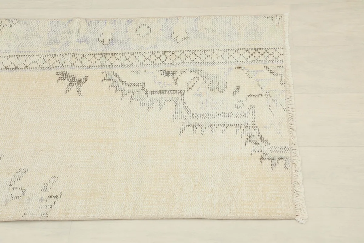 Close-up detail of the upper right section of the rug, showing faded gray and blue patterns