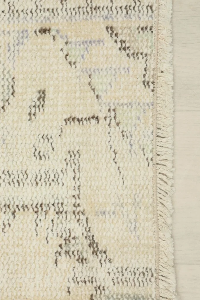 Close-up of the short, natural fringe and the edge of the cream and gray vintage rug