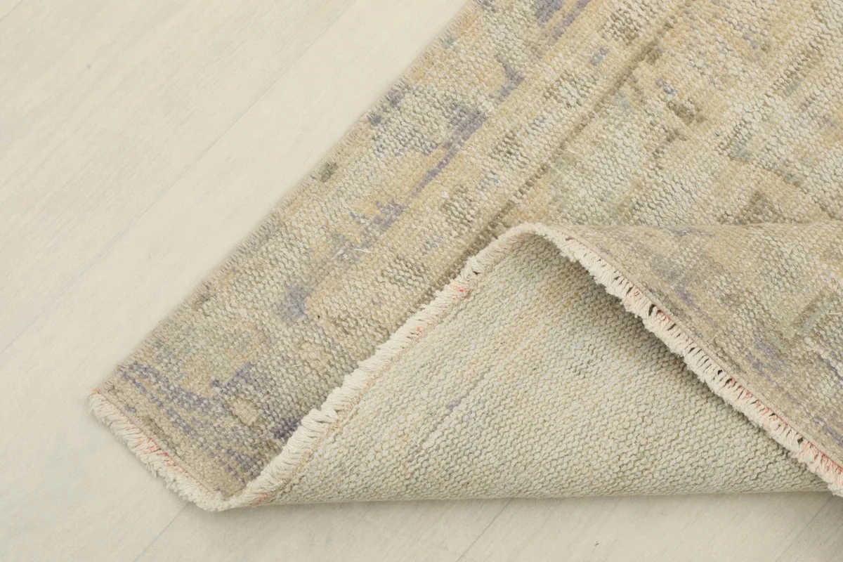 Corner of the rug folded back, revealing the cotton foundation and reverse side