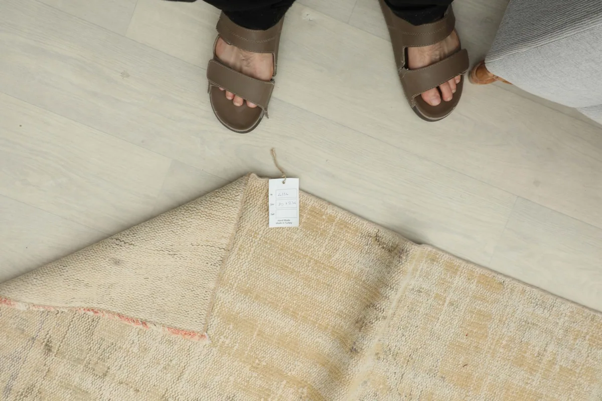 Overhead view of a person standing near the folded rug, showing the product tag