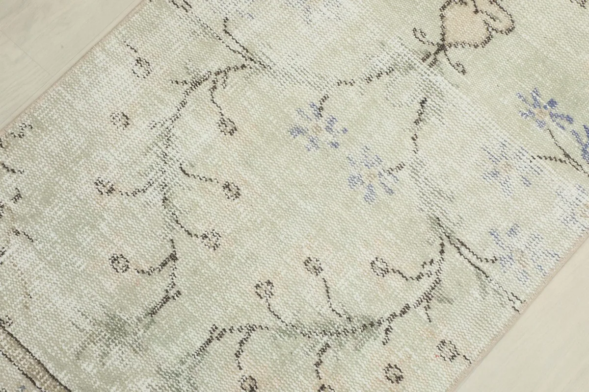 Close-up of the low pile and faded blue floral details on the cream field.