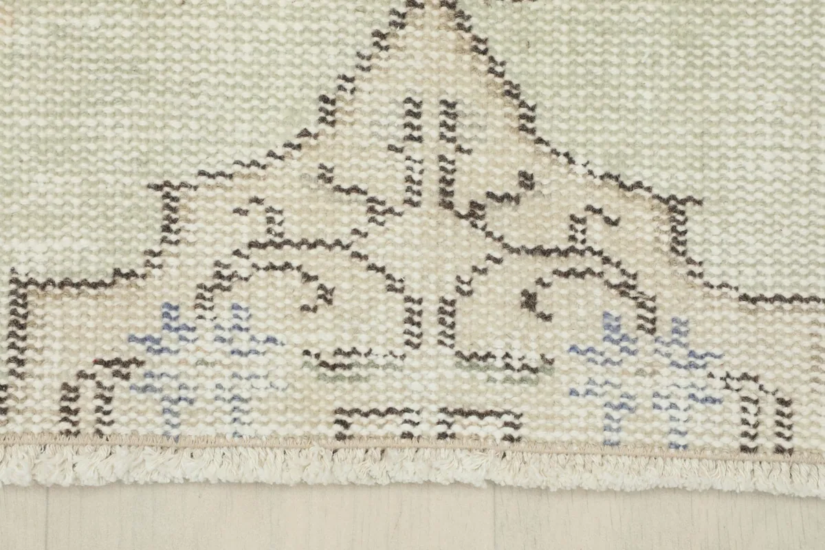 Detail showing the short, natural fringe and the end of the rug with a geometric pattern.
