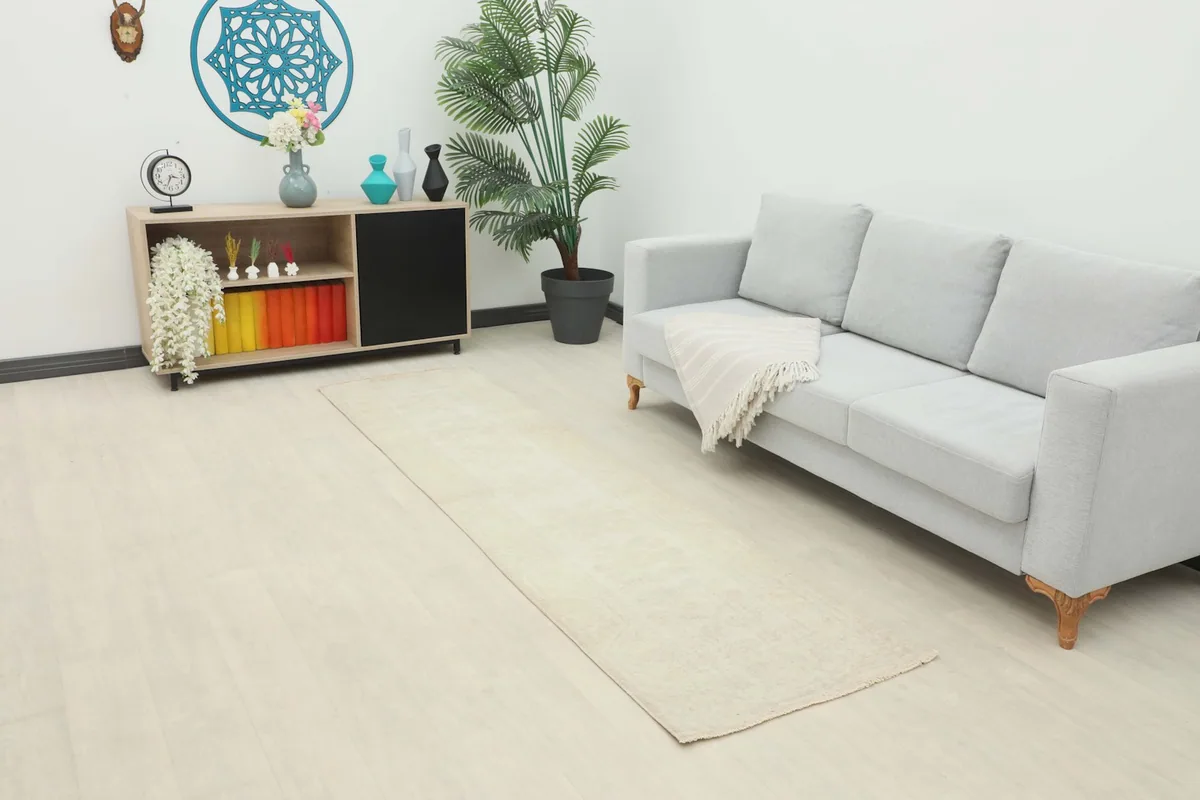 Cream vintage runner in a modern living room setting next to a gray sofa and wooden shelf.