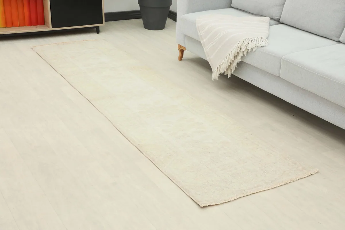 Angle view of the cream runner extending from a gray sofa in a contemporary room.