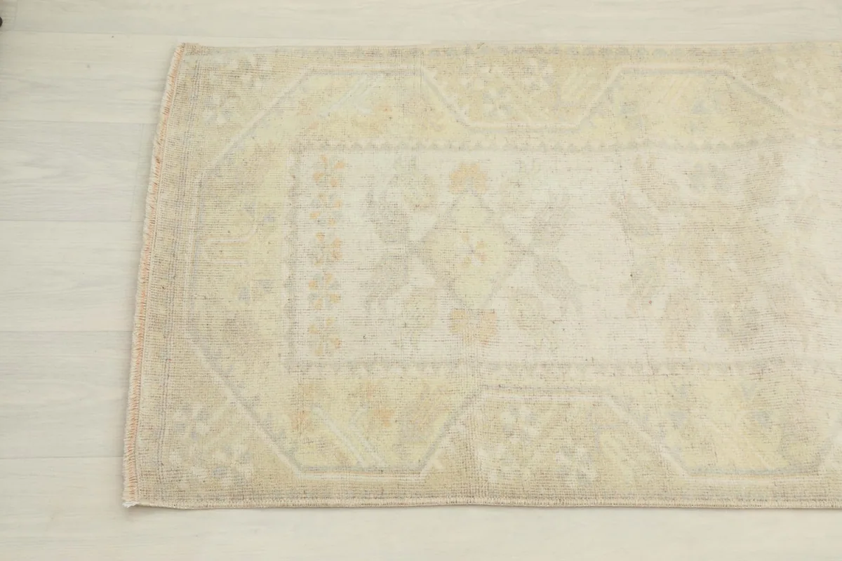 Detailed view of the corner of the cream runner, showing the distressed texture and faint motifs.