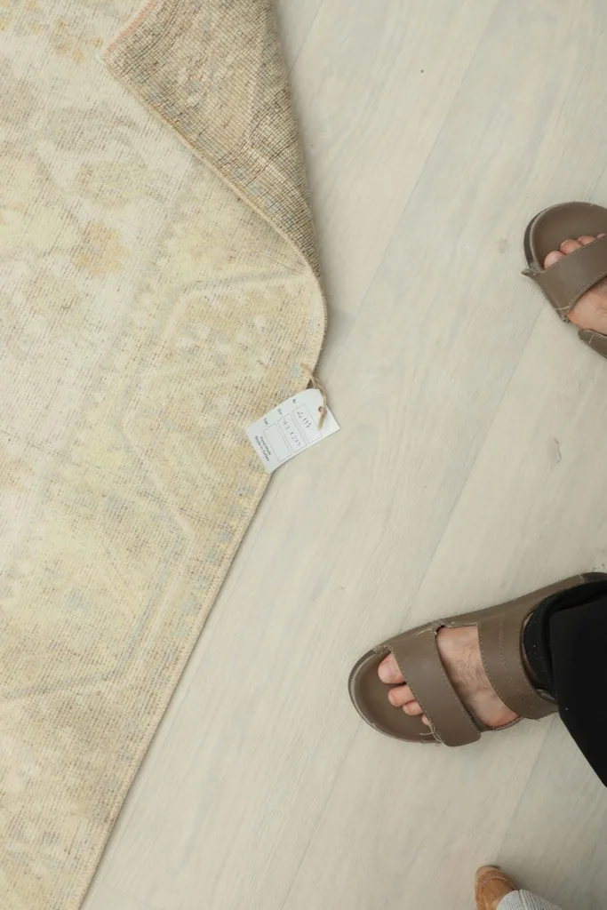 Overhead view showing the rug's label and a person's feet for scale.