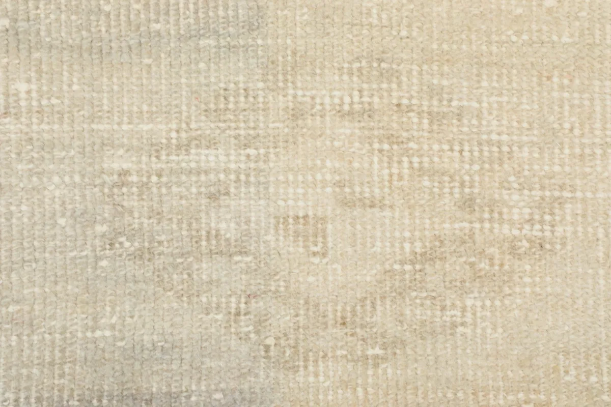 Very close-up of the rug's low pile, showing individual wool knots and subtle color variations