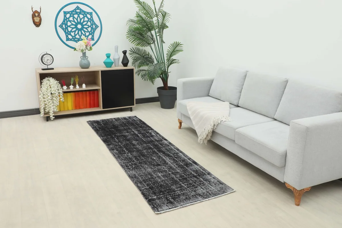 Charcoal runner rug placed in a living room setting with a light gray sofa