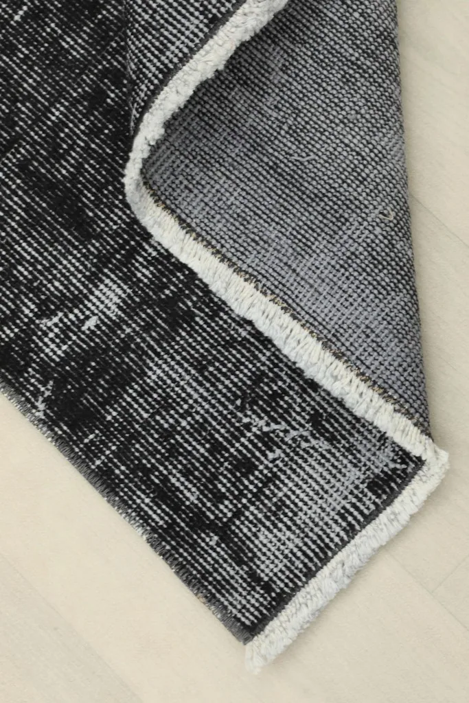 Corner of the rug folded to show the hand-knotted construction and cotton foundation