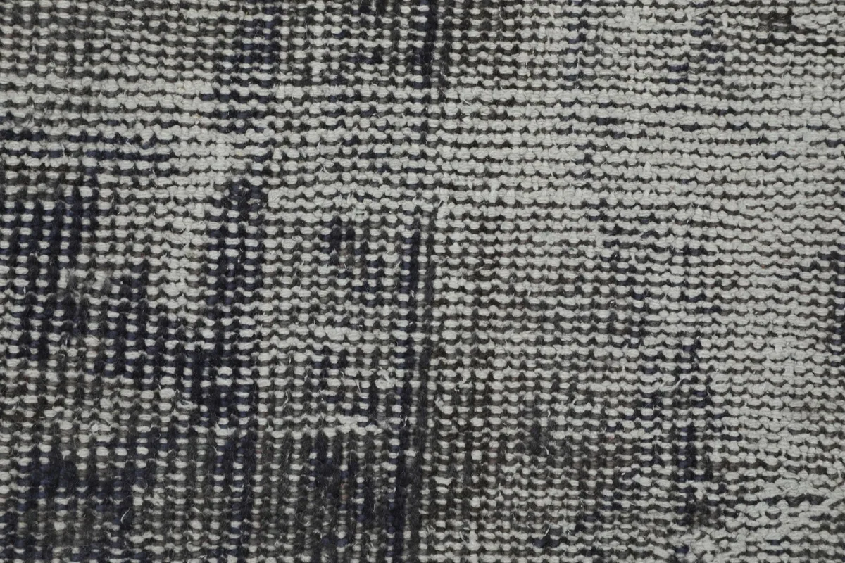 Extreme close-up of the rug's surface, revealing the intricate hand-knotted wool pile and cotton foundation.