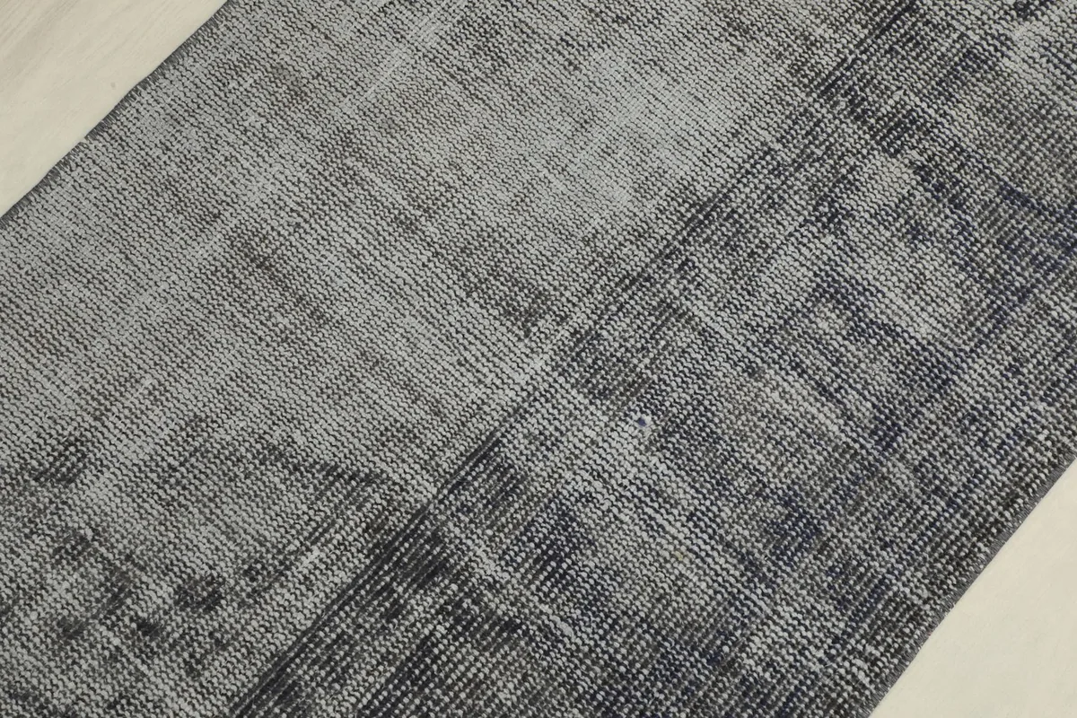Detailed view of the low pile and weave of the charcoal and gray hand-knotted rug, showing textural variations.