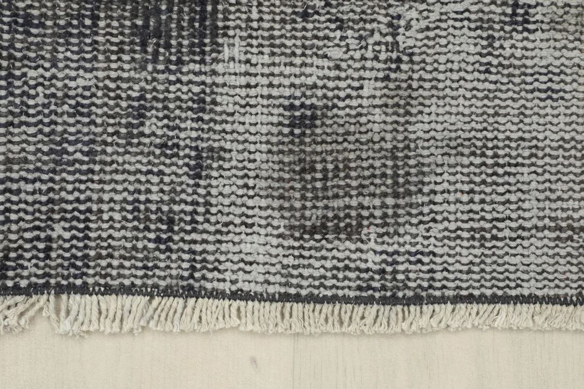 Close-up of the natural cotton fringe on one end of the charcoal and gray vintage area rug.