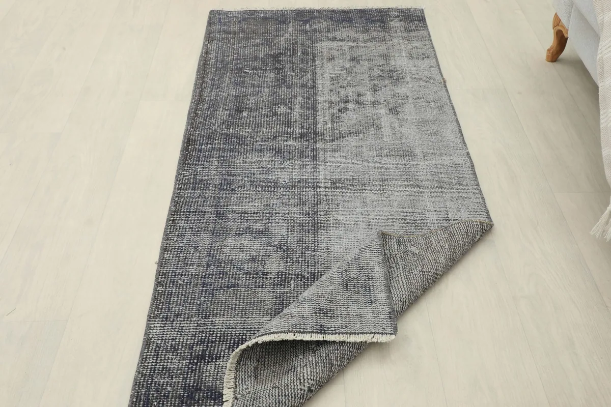 View of the rug with a corner folded back, showing the back of the hand-knotted wool pile and cotton foundation.
