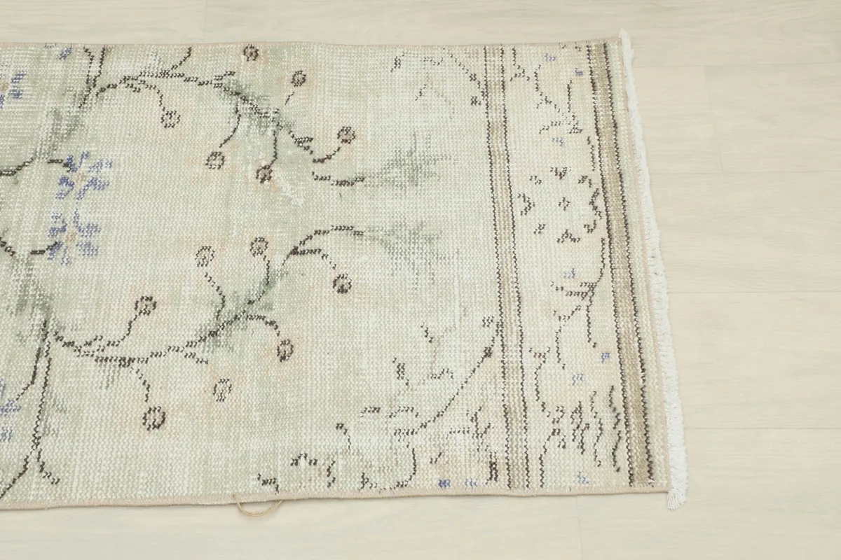 Close-up detail of the rug's cream field with blue floral patterns and geometric border