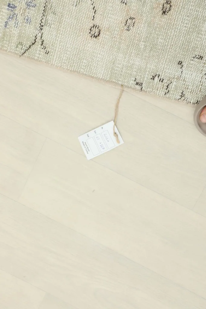 A partial view of the rug with a size tag on the light wooden floor