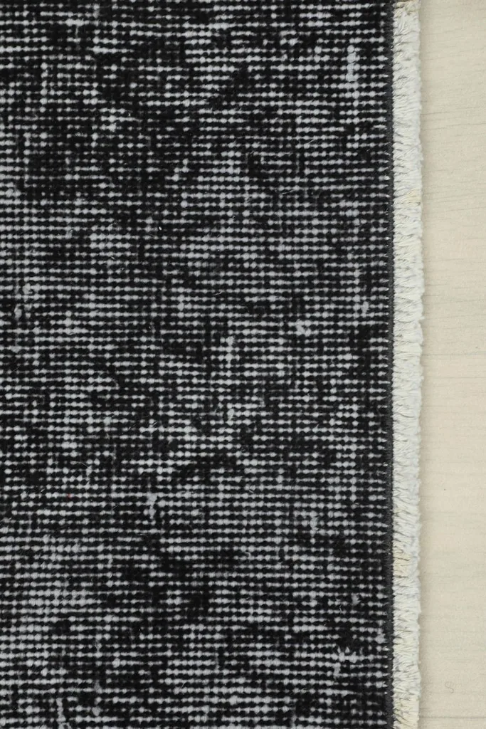 Close-up of the rug's edge and fringe, showing the cotton foundation and the tightly woven wool pile.