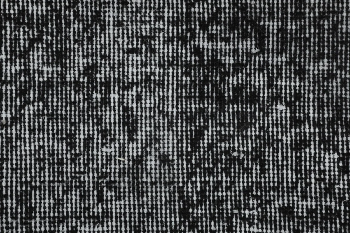Extreme close-up of the low wool pile, revealing the hand-knotted texture and distressed pattern.