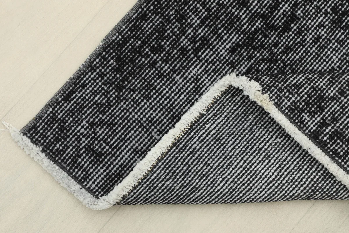 Corner folded back to reveal the cotton foundation and reverse side of the hand-knotted rug