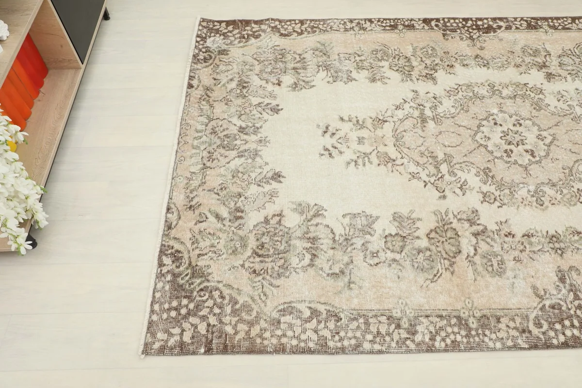 Angled perspective of the rug, capturing the blend of ivory and tan colors with subtle brown motifs.