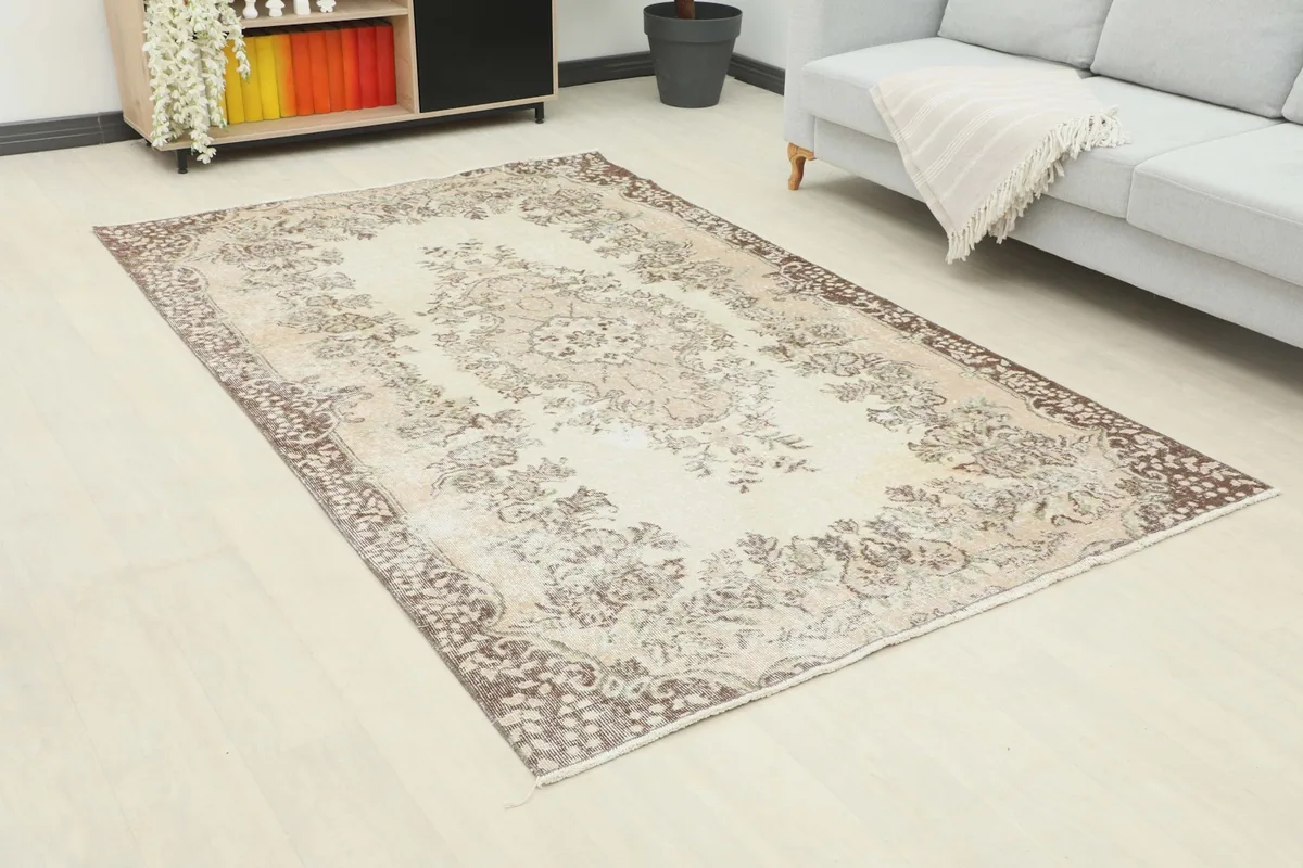 Angled view of the vintage ivory tan rug in a living room, highlighting its medium size and placement.