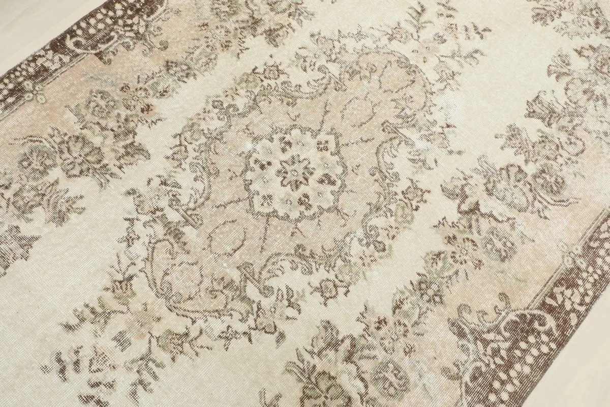 Detailed view of the central floral medallion and surrounding patterns on the vintage rug.