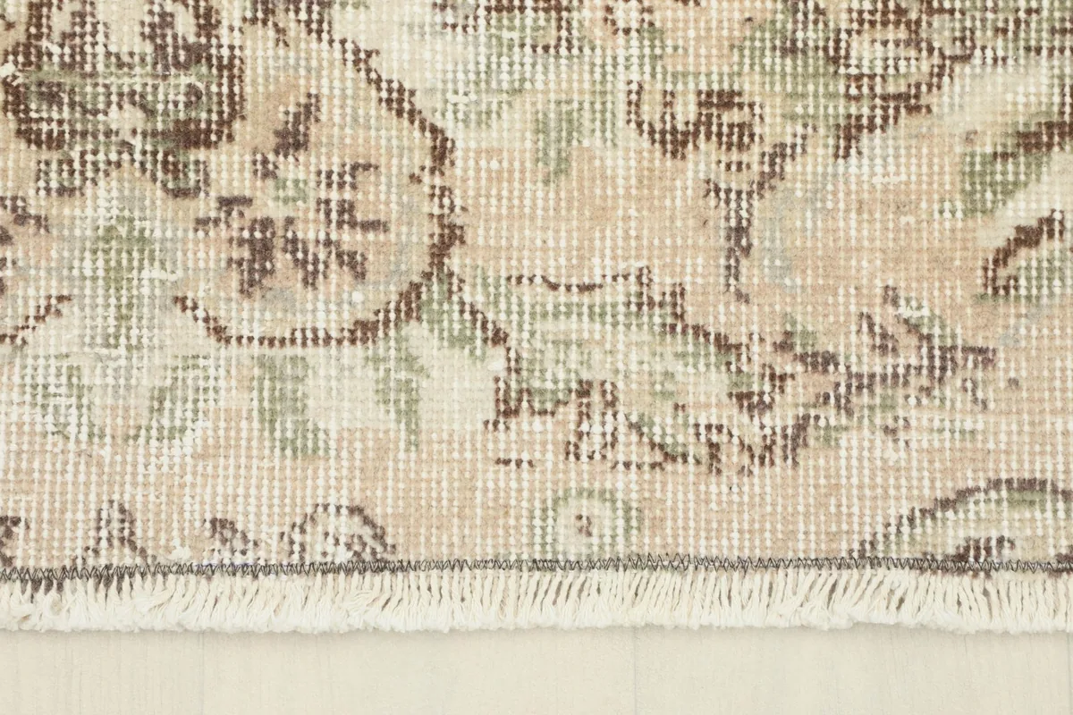 Close-up of the rug's short, hand-finished fringe and edge, showing the cotton foundation.