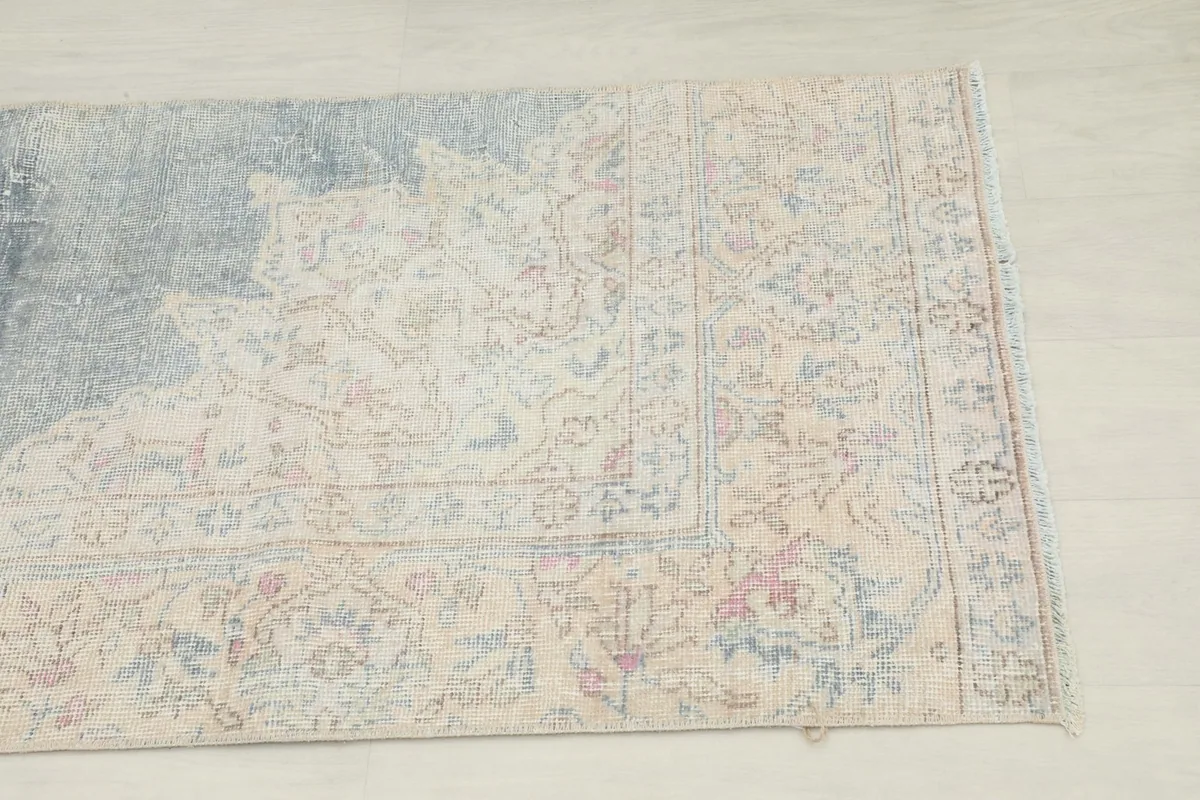 Close-up of the distressed beige field and floral border design on the vintage rug