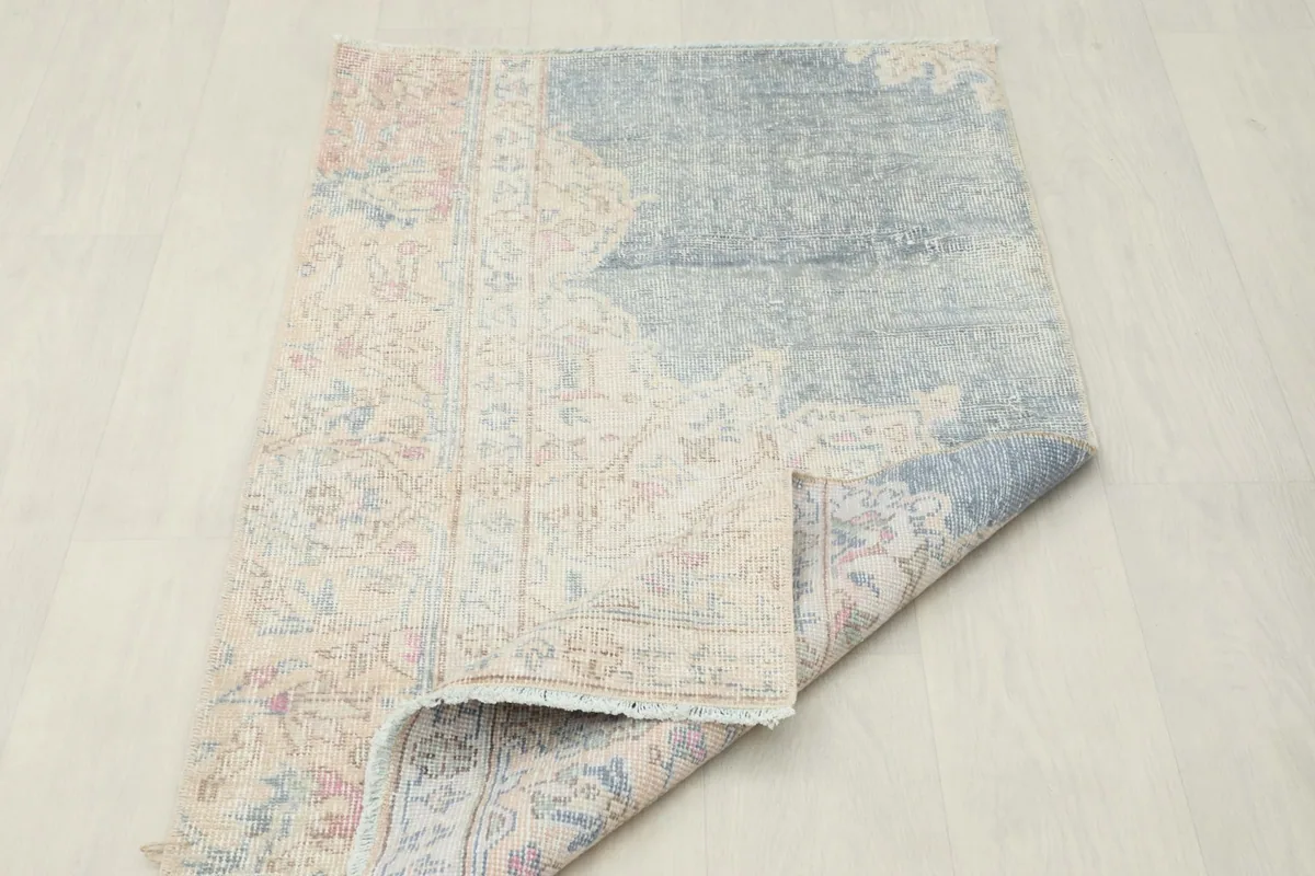 View of the rug partially folded, revealing the back of the hand-knotted wool on cotton foundation