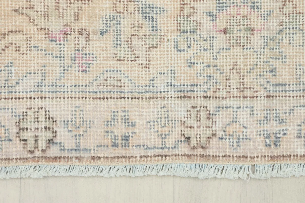 Close-up of the natural fringe and the detailed border pattern of the vintage area rug