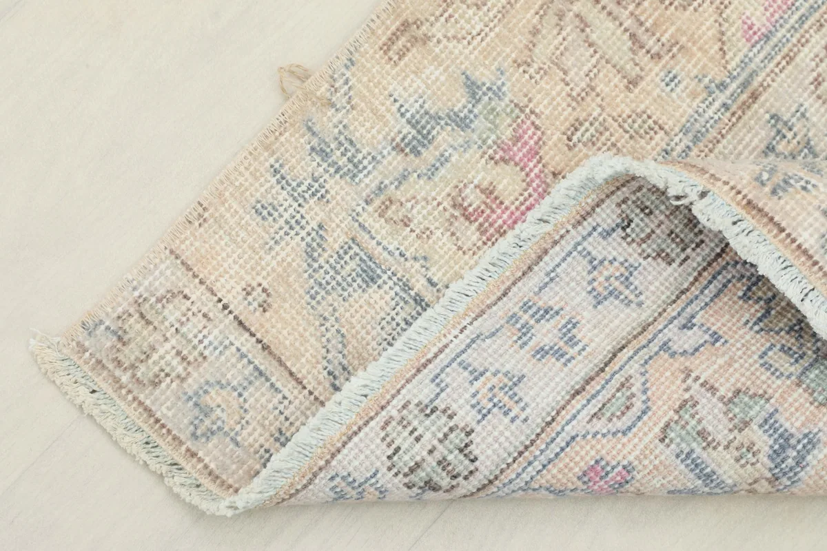 Corner of the rug folded to show the cotton foundation and the reverse side of the hand-knotting