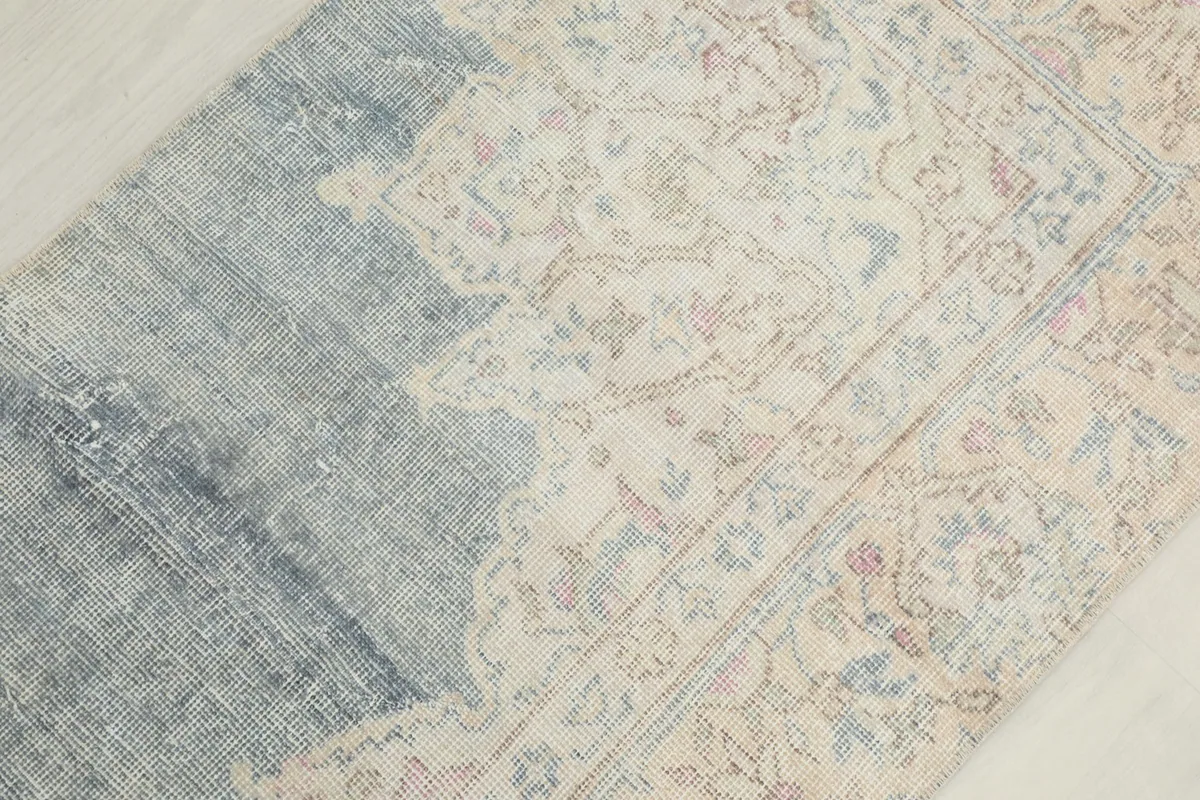 Overhead close-up of the rug's surface, highlighting the faded blue and beige colors and motifs