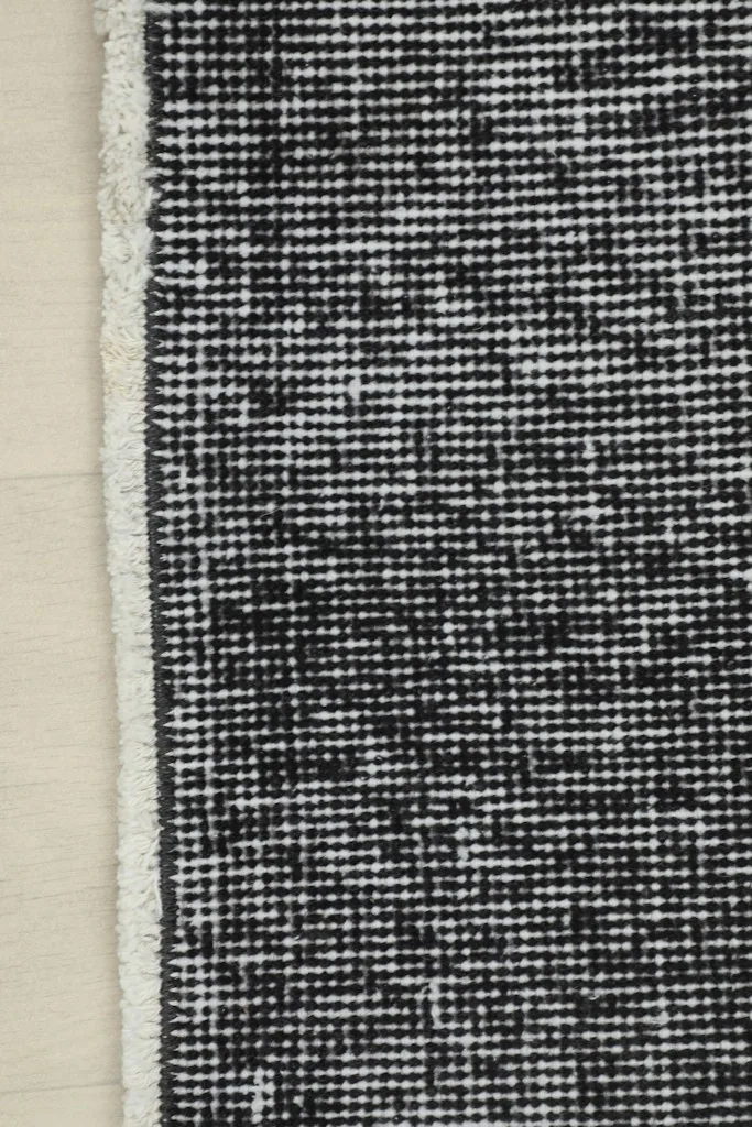 Detail of the rug's edge, showing the hand-knotted construction and short fringe