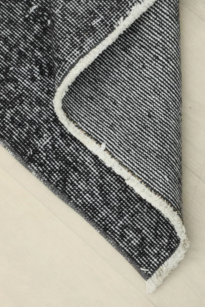 Corner of the rug folded to reveal the cotton foundation and reverse side of the knots