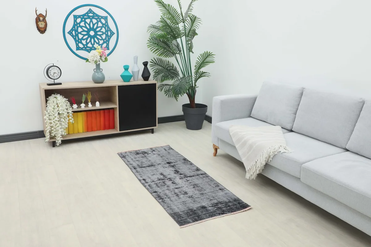 Vintage charcoal and gray runner rug placed in a modern living room setting next to a light gray sofa.