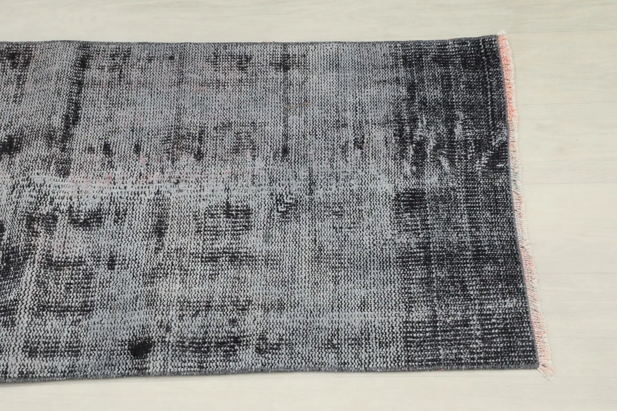 Close-up detail of the rug's distressed charcoal and gray pile, showing texture and color variation.