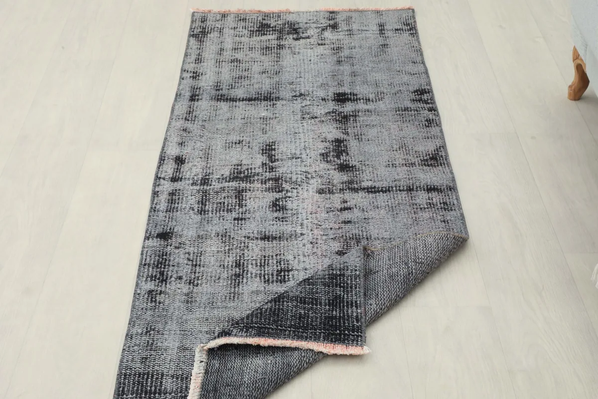 View of the rug with one corner flipped to show the back of the hand-knotted cotton foundation.