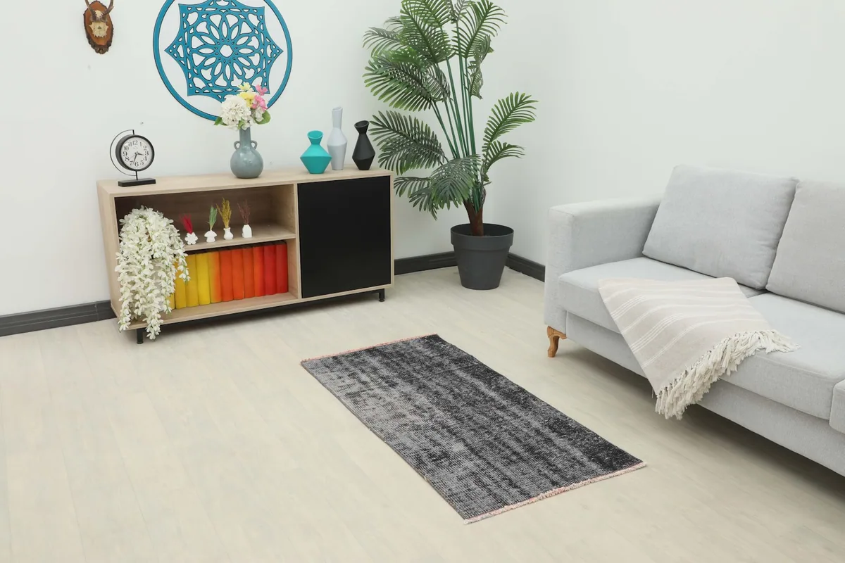 Charcoal gray distressed rug in a modern living room setting with a sofa and cabinet