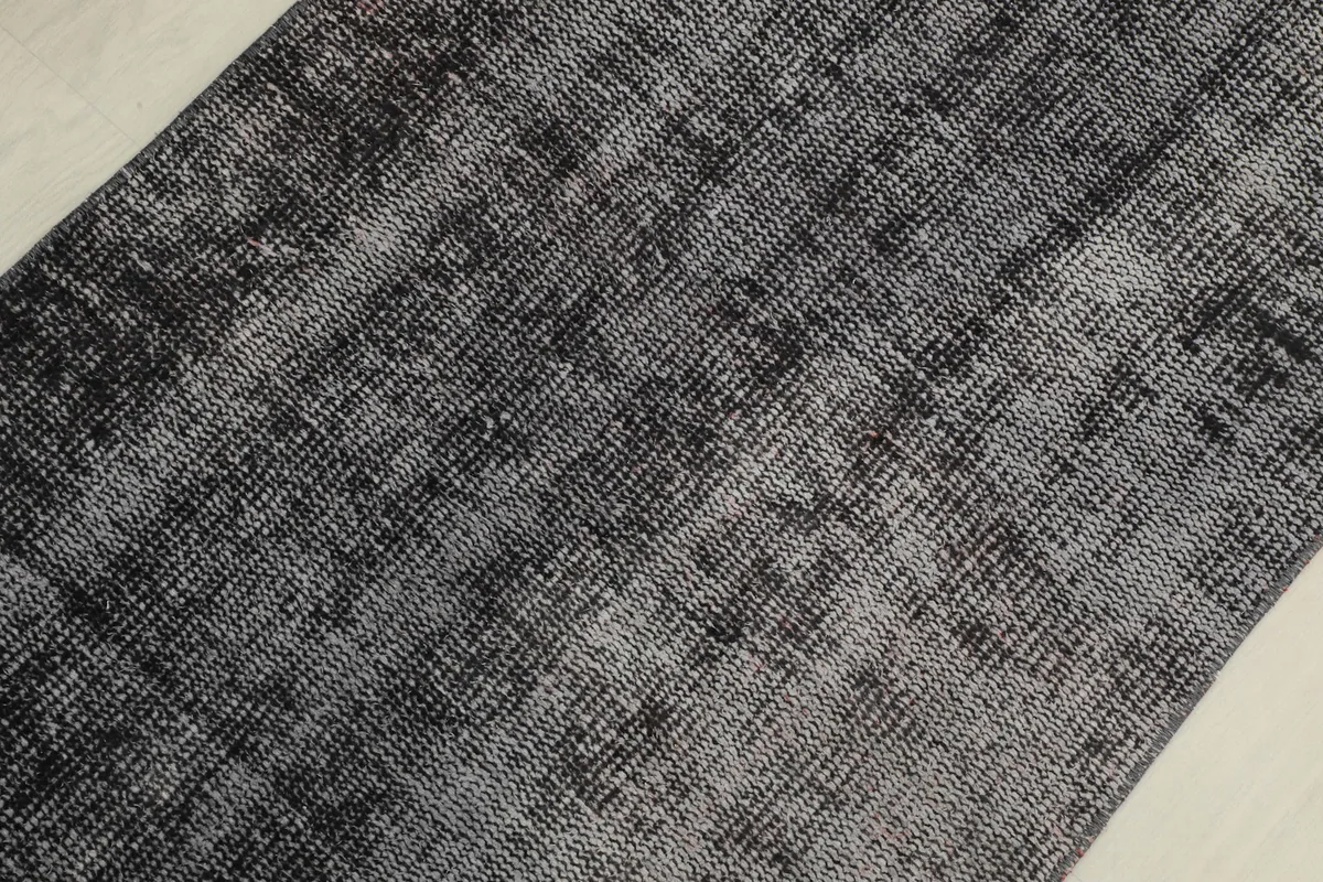 Detailed view of the rug's texture and varying shades of charcoal, black, and gray