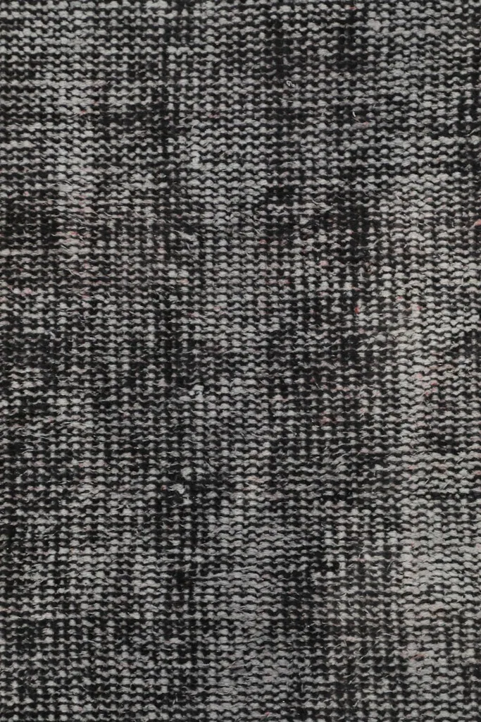 Macro view of the low wool pile, revealing the hand-knotted construction and color variations