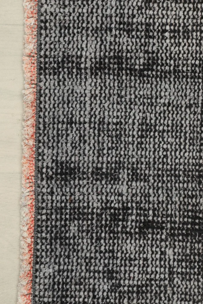 Close-up of the rug's edge, showing the subtle rose-colored selvedge and short fringe
