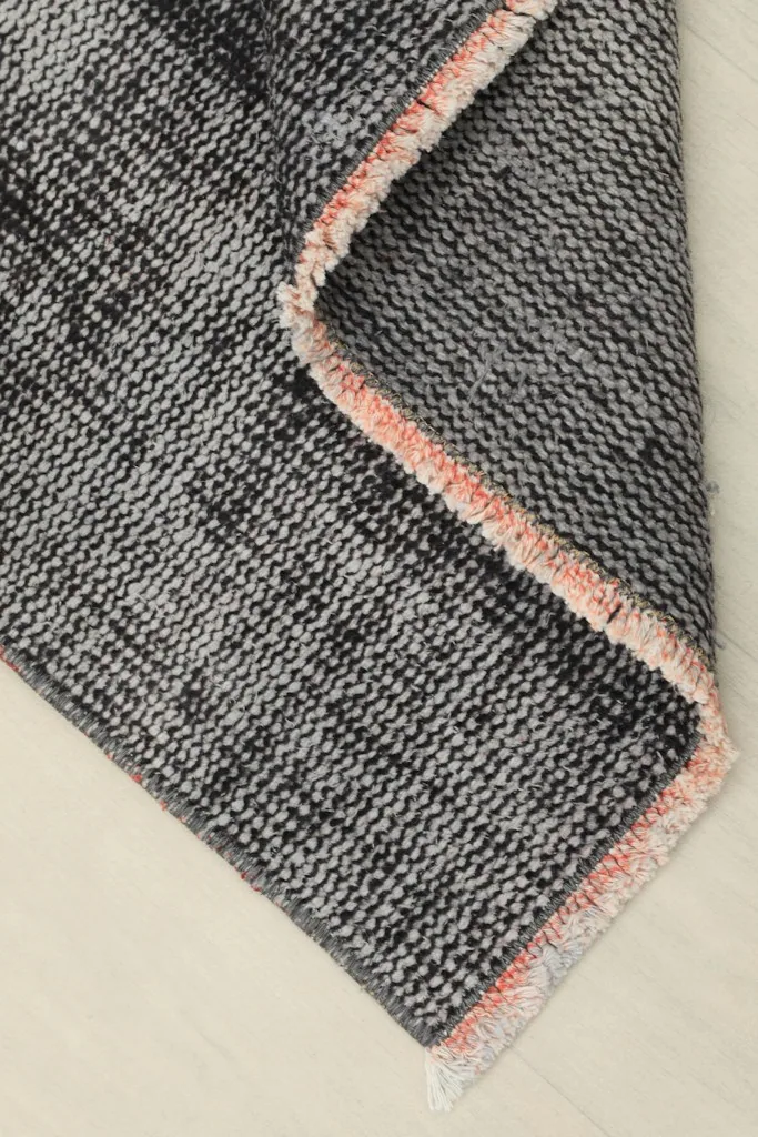 Folded corner of the rug, showing the reverse side and the hand-knotted wool on cotton foundation