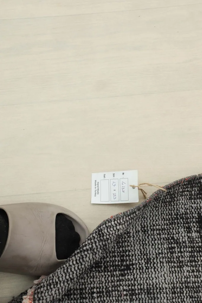 Top-down view of the rug's label with size information, next to a slipper for scale