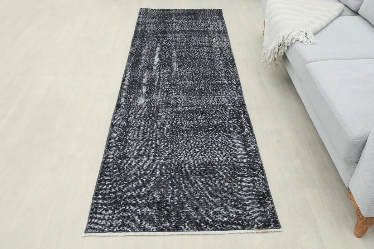 Full view of the charcoal runner rug in a room, positioned in front of a light gray sofa.