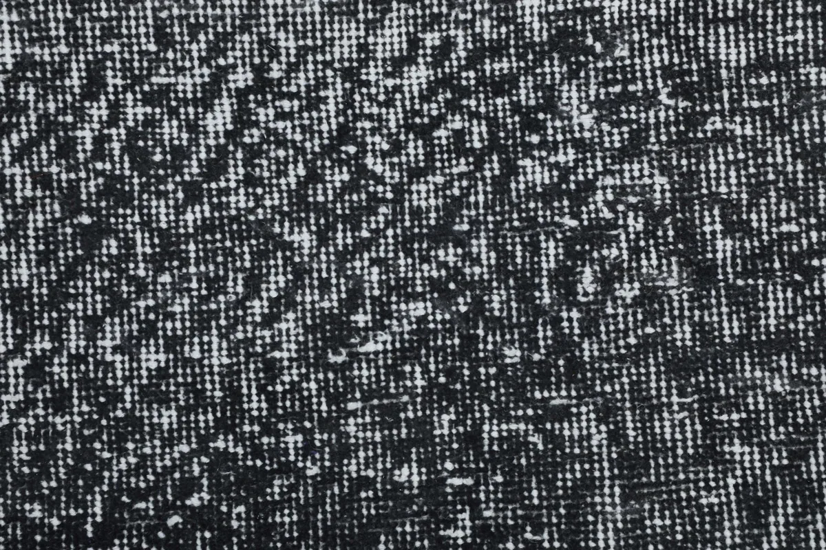 Detailed close-up of the rug's low pile and the intricate, faded abstract pattern in charcoal and ivory.