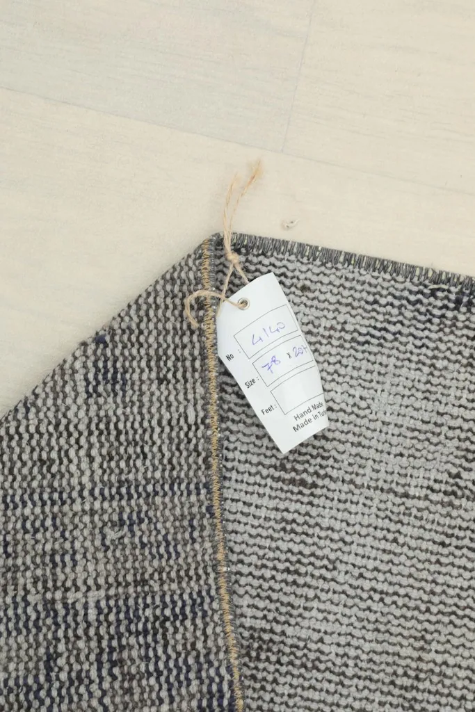 Corner of the rug with a tag, showing its handmade origin and details