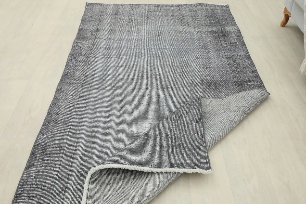 Partial view of the rug's back, revealing the hand-knotted cotton foundation