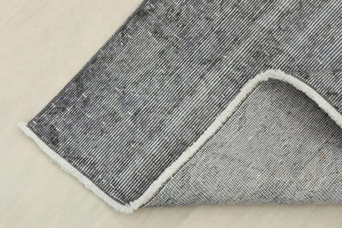 Corner of the rug folded back, showing the wool pile and cotton foundation