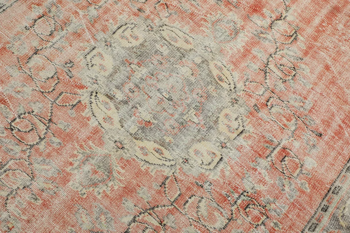 Close-up of the central medallion motif in gray and ivory against the faded rust background.